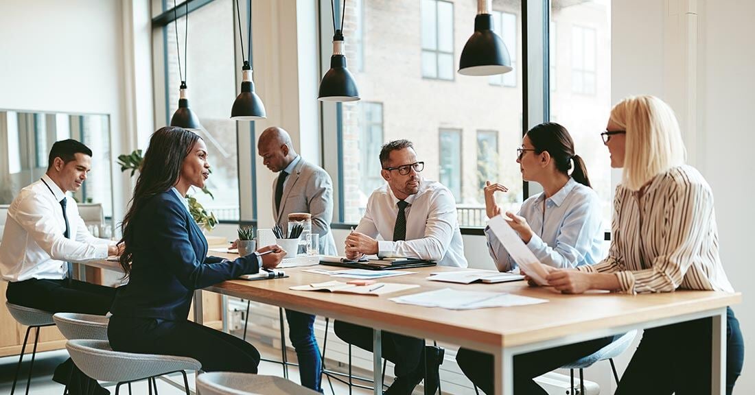 Several professionals set together in a modern office at a long table having a meeting