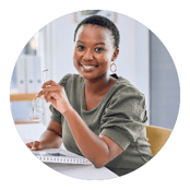 black woman holding her glasses and a notebook facing the camera and smiling