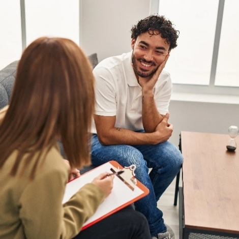 A woman with a clipboard faces a smiling man in a meeting