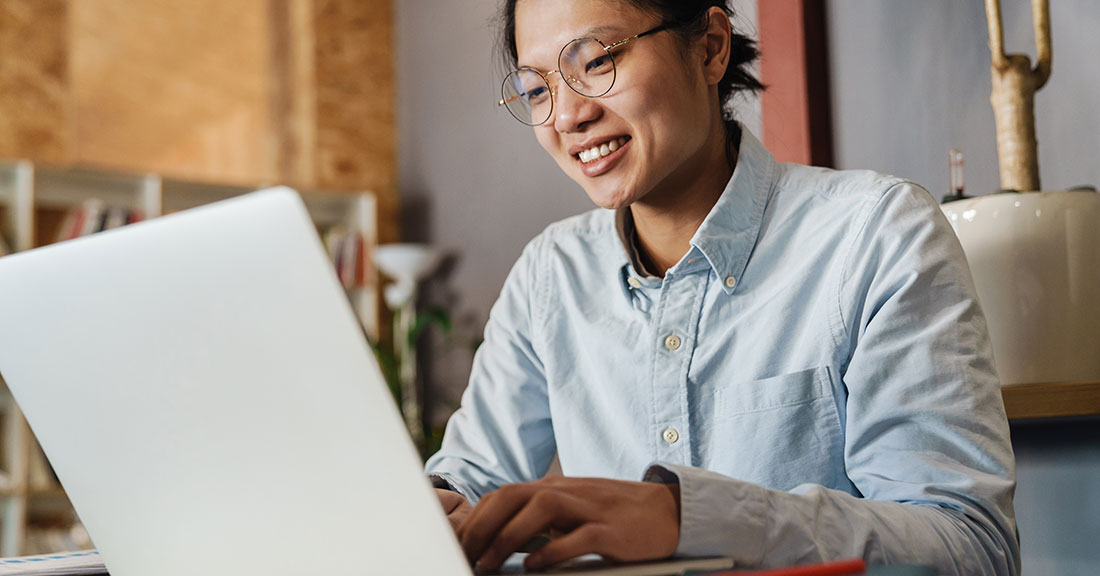 Person smiling and using a laptop computer