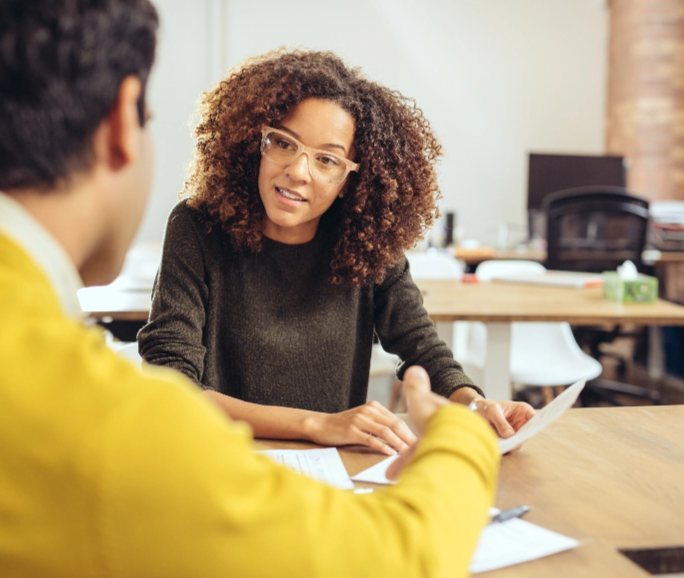 Woman in green sweater collaborating with a man and paperwork