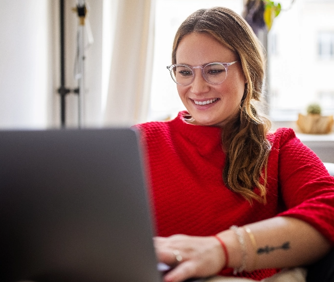 Woman in red sweater using a laptop smiling