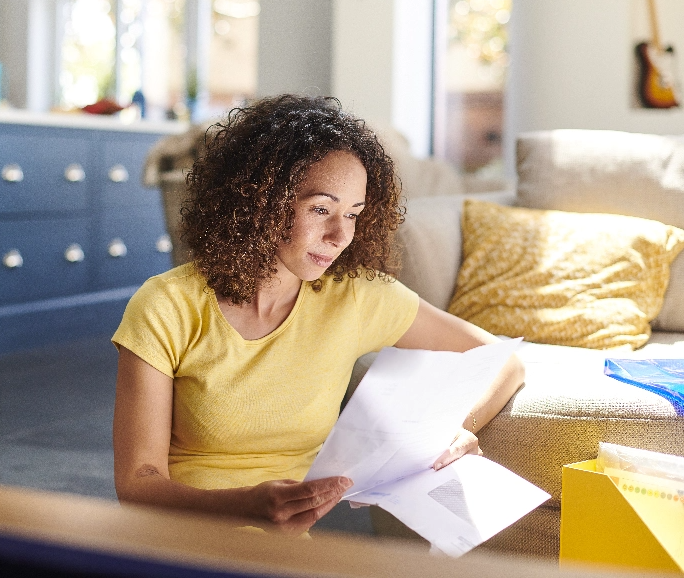Woman in yellow shrit reviewing documents in her livingroom