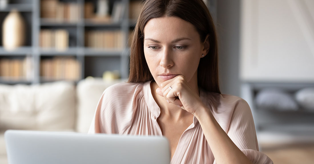 Thoughtful woman looking at laptop screen, pensively considering how to handle an upcoming change.