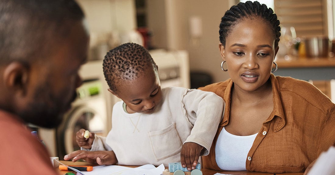 Two parents and their child at a table reviewing documents.